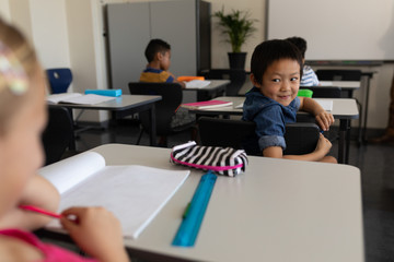 Happy schoolboy looking back in classroom