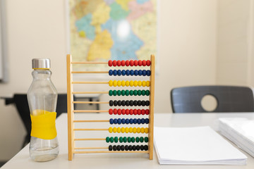 Water bottle, abacus and bunch of paper on the desk in school