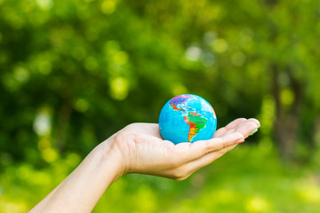 little globe in hand on nature background