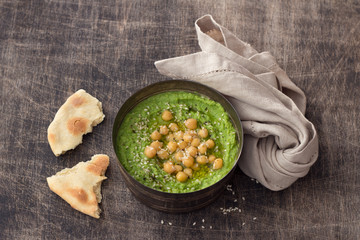 Green parsley hummus with chickpeas, sesame and homemade pita on a wooden table. delicious healthy...