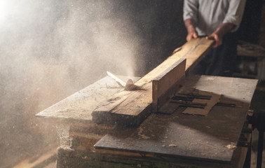 Carpenter cutting a wooden plank with a carpentry machine. - obrazy, fototapety, plakaty