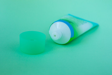 Tube with cream on a mint background, cosmetics care concept, minimalistic style.