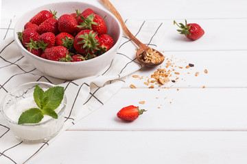 Fresh strwberries and yogurt on the white table close-up