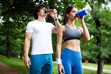 Athletic couple friend drinking water after running
