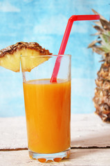 Pineapple cocktail or juice in glass bottles with straws with ice and pineapples on a blue or pink background