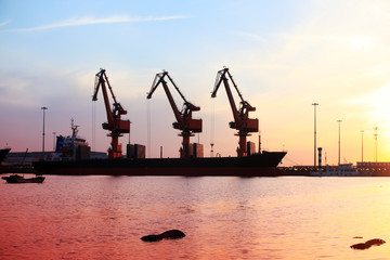 Fototapeta premium Gantry crane and cargo ship in the evening