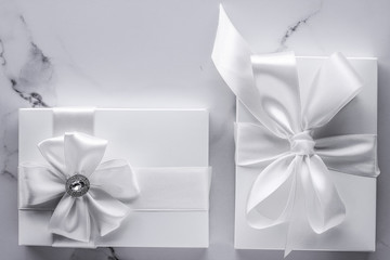 Luxury wedding gifts with silk bow and ribbons on marble background
