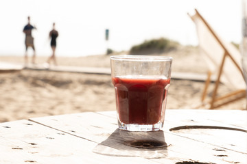 Verre de jus de tomate cocktail sur une table en bois devant la mer