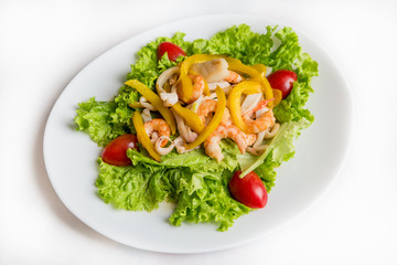 Fried shrimps on a plate with vegetable salad on white background.