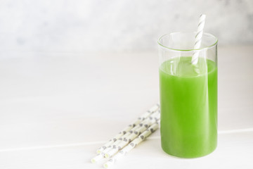 Freshly blended green smoothie in in a glass with straws on the table. Detox vegetable juice....