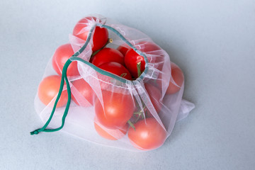 Tomatoes in eco-friendly packaging. Reusable bags for vegetables and fruits. Shopping in the store, retail. Eco-friendly packaging.