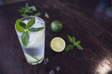 Mojito cocktail on a dark wooden background. Fresh lime juice with mint and ice. Cooling drink