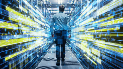 Shot of a Young It Specialist Walking through Corridor in Working Data Center Full of Rack Servers...