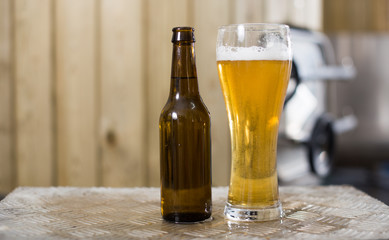 bottle and glass with gold beer on the background of barrels for fermentation