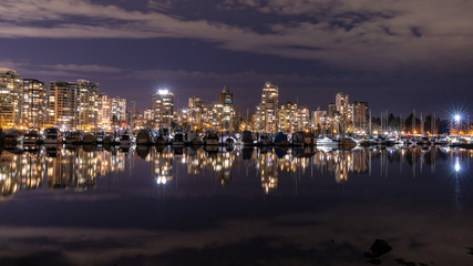 Fototapeta premium Vancouver, BC \ Canada - 13 March 2019: A night long exposure photo of marina inside Burrard Inlet of Vancouver Harbor with many yachts and boats against colorful illuminated city skyline