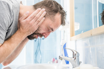 Man washing his face in bathroom