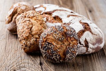 Gold rustic crusty loaves of bread and buns on wooden background. Still life captured from above...