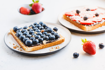 Close-up of breakfast sweet toast with chocolate spread, hucklberry and crashed almond.