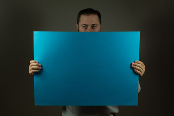 Beard man holding a color cartboard in front of his face. Copy space