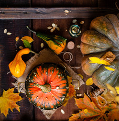 autumn still life with pumpkins and bouquet of fall leaves on brown rustic table
