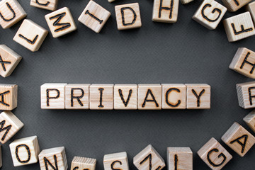 Obraz premium the word privacy wooden cubes with burnt letters, data confidentiality, gray background top view, scattered cubes around random letters