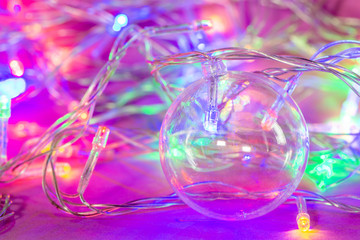 Beautiful transparent Christmas ball with lights from the garlands on the background.
