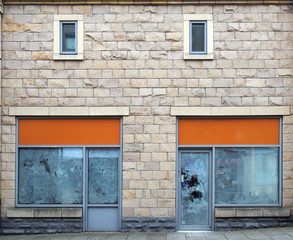 Fototapeta na wymiar two empty abandoned shops on a street with whitewashed empty windows and blank store signs