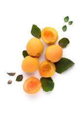 Ripe and tasty apricots with mint leaves on a white background.