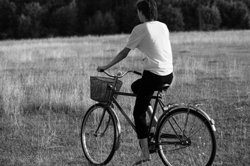 Fototapeta premium Happy girl rides a classic bike among beautiful nature.