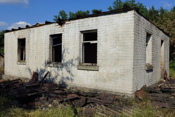 old gray burnt brick house with empty black windows on the street