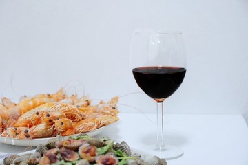 Blurred image of steamed shrimp, steamed cockles in white plate and wine on white table, set of dinner, Copy space