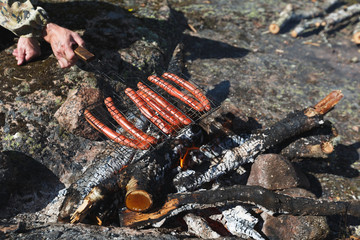man fries sausages on the fire