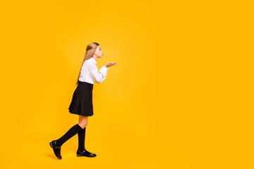 Full length body size profile side view of nice attractive lovely sweet cheerful cheery straight-haired pre-teen girl sending kiss copy space isolated on bright vivid shine yellow background