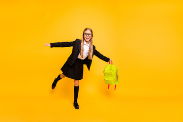 Full size photo of cheerful child wear eyeglasses eyewear raising leg isolated over yellow background