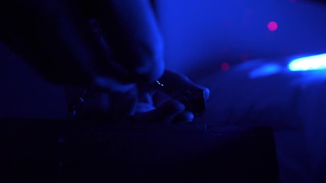 The man picks up a small key on a chain, brings it to a small lock on the iron chest and unlocks it. Close-up of male hands. The dark room, in the blue muffled light.