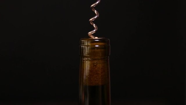 Opening wine bottle with corkscrew against black background, closeup