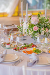 Assorted greenery and different colors flowers in a glass vase on a table for a wedding or birthday party
