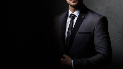 Obraz na płótnie Canvas Young handsome successful and confident bearded business man in a suit. Isolated on dark background, copy space.