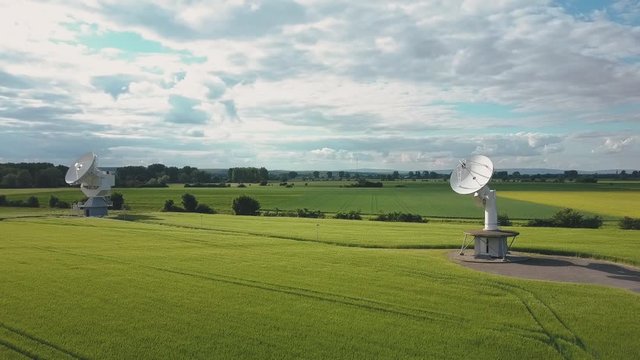 Aerial view parabolic satellite communication dish in green fields Riedstadt Germany in 4k
