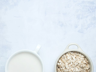 Obraz na płótnie Canvas Oat milk drink in white cup and cereal flakes on kitchen bench. Flat lay. Copy space.