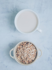 Oat milk drink in white cup and cereal flakes on kitchen bench. Flat lay. Copy space.