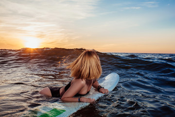 Beautiful sexy surfer girl on the beach at sunset