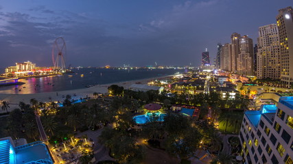 Aerial view of beach and tourists walking in JBR with skyscrapers day to night timelapse in Dubai, UAE