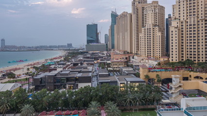 Fototapeta premium Aerial view of beach and tourists walking in JBR with skyscrapers day to night timelapse in Dubai, UAE