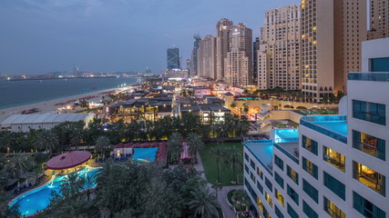 Fototapeta premium Aerial view of beach and tourists walking in JBR with skyscrapers day to night timelapse in Dubai, UAE