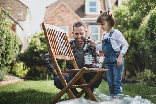 Father and Daughter painting garden furniture together