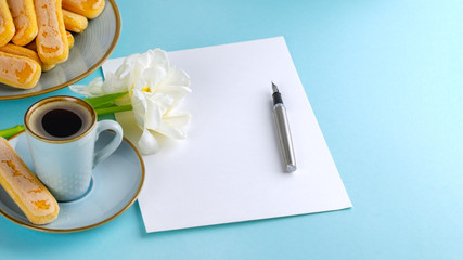 A sheet of white paper is empty on a blue background with an ink pen . Copy space.