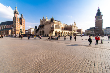 Obraz premium Krakow, Poland - April, 2019: Two Horses In Old-fashioned Coach At Old Town Square In Cloudy Summer Day. St. Mary's Basilica Famous Landmark On Background. Church of Our Lady Assumed into Heaven.