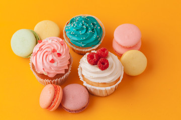 Delicious cupcakes with icing on a yellow background