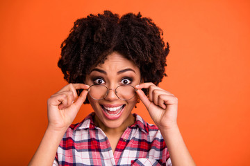 Close-up portrait of nice cute attractive cheerful cheery crazy glad positive optimistic wavy-haired lady nerd wearing checked shirt touching glasses isolated on bright vivid shine orange background